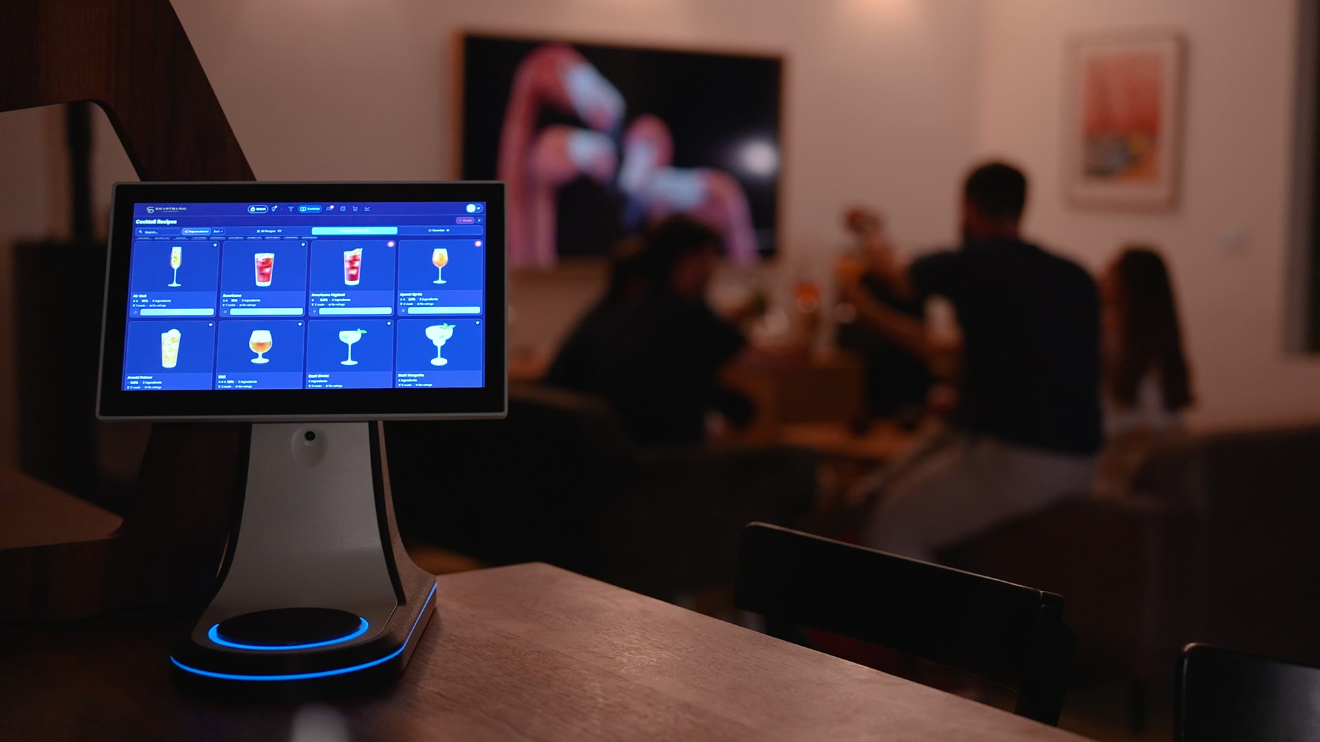 SmartBarIQ Solo on the counter at a party at home, its cocktail menu on screen and the scale ring glowing