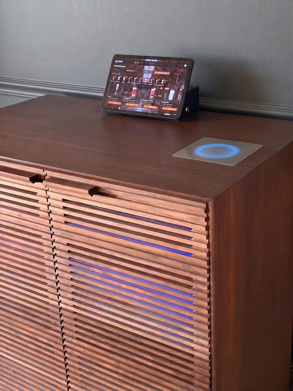 The cabinet's wood top with the tablet docked and a wireless charging ring